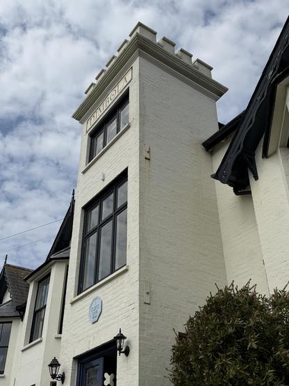 Dimbola building which has a tower like structure as part of the main building with windows, and a blue plaque