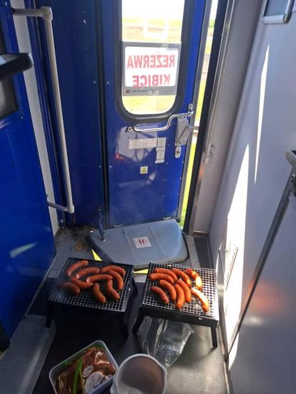 some guy grilling sausages in front of a train entrance with the door being slightly open and the train running