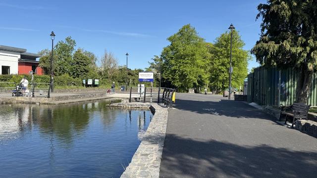 Photo, landscape, exterior: A canal harbour. Trees beyond and to the right. A sign indicates Maynooth Harbour’. It’s a bright day.