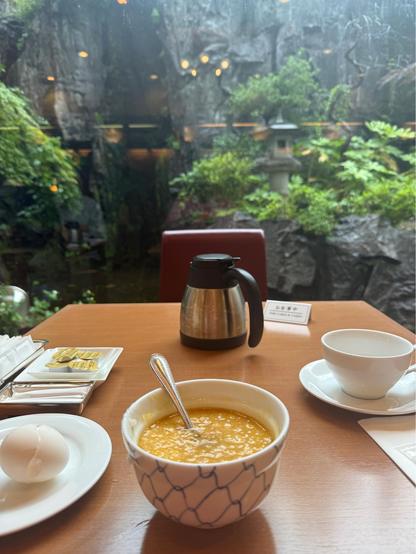 Tamago Kake Gohan in a bowl in front of a small pot of coffee, background, a rainy garden