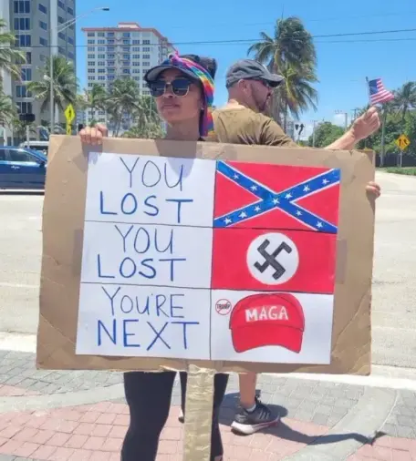 Jeune femme tenant un panneau de manif, 6 cases, de haut en bas et de gauche à droite, "You lost", drapeau sudiste, "You lost", croix gammée, "Your're next", casquette rouge MAGA