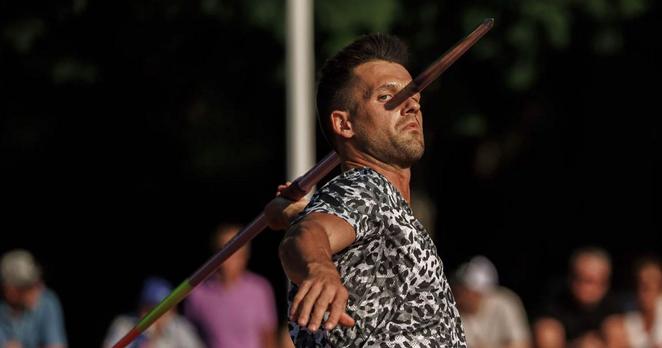 A man about to throw a javelin. The javelin is casting a shadow on his face that aligns perfectly, making it appear that the javelin is piercing his head.