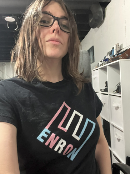 me wearing a black shirt with an Enron logo in the trans pride colours