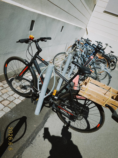 A photo of a black and red bike. It has a wooden crate on the back and a tiger bell.