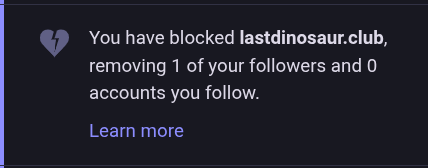A Mastodon notification on a dark background featuring a broken heart icon. The text reads: "You have blocked lastdinosaur.club, removing 1 of your followers and 0 accounts you follow." A "Learn more" link is visible at the bottom.