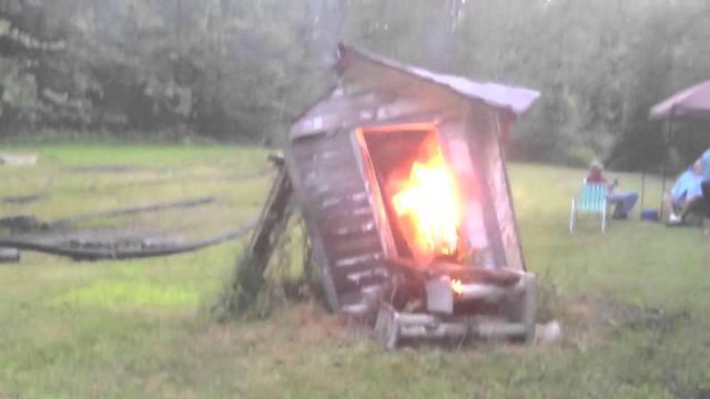 There is a biggish fire inside an old and falling down outhouse.