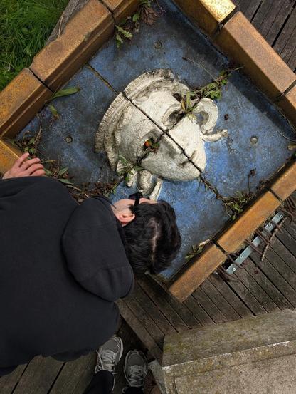 Little sculpture of a head with a flower in one eye, and me trying to figure out if the flower was put there or if it’s actually growing from the eye