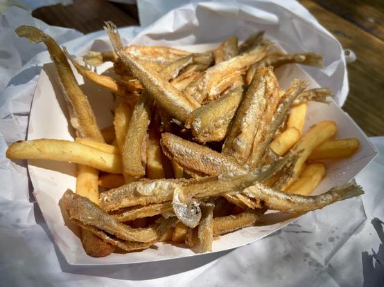 A paper tray full of fried smelt and French fries