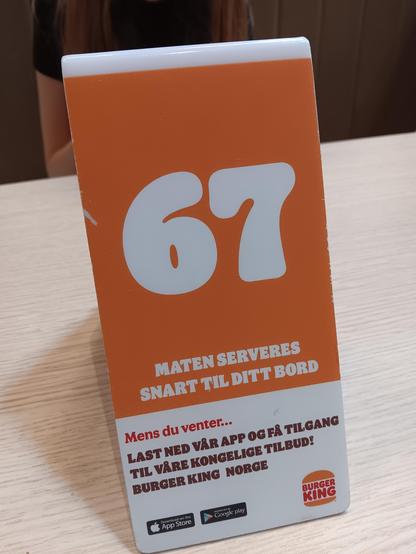 A table marker from burger king with the number 67