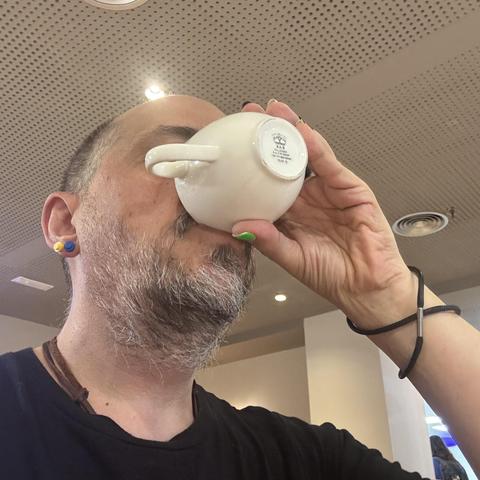 «Alguien» terminándose el café de una taza. Alguien con pendientes de lego, amarillo y azul, uñas estupendas, y un cordoncillo con doble vuelta en la muñeca.