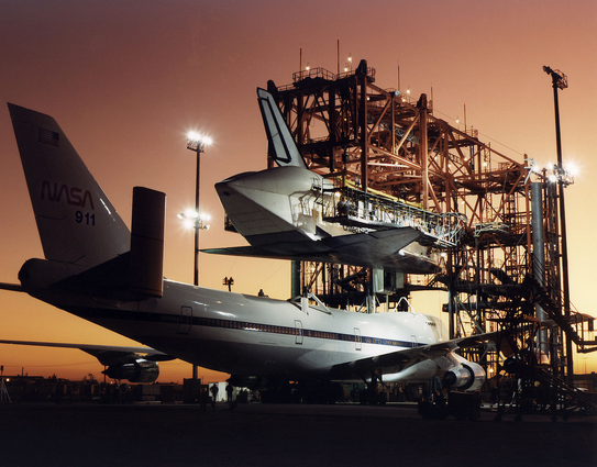Evening light begins to fade at NASA's Ames-Dryden Flight Research Facility (later redesignated Dryden Flight Research Center), Edwards, California, as technicians begin the task of mounting the Space Shuttle Atlantis atop NASA's 747 Shuttle Carrier Aircraft (NASA #911) for the ferry flight back to the Kennedy Space Center, Florida, following its STS-44 flight 24 November-1 December 1991. Post-flight servicing of the orbiters, and the mating operation, is carried out at Dryden at the Mate-Demate Device (MDD), the large gantry-like structure that hoists the spacecraft to various levels during post-space flight processing and attachment to the 747.

Date 	Taken on 7 December 1991
Source 	http://www.dfrc.nasa.gov/Gallery/Photo/STS-MDD/HTML/EC91-659-2.html (direct link)
Author 	NASA/Jim Ross