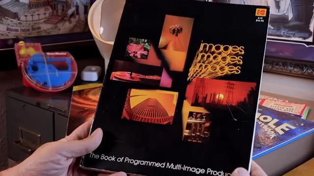 images images images: The Book of Programmed Multi-Image Production - a large format paperback book with various small images collaged on a black background. It's being held in a  person's hands in front of various disney and view-master paraphernalia. It looks very 1979.