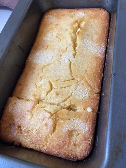 Metal loaf tune. A rectangular view of corn bread. The white marks are where butter has melted. One cut across lower side