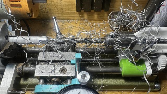 drill bit on a lathe wrapped in long strings of aluminum from boring a 50mm deep hole in a knurled part