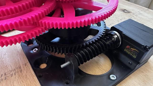 closeup of a servo with a worm gear driving a helical gear, mounted on a wooden board