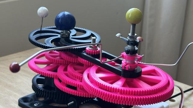 view of a geocentric orrery with colored balls for the planets and lots and lots of gears