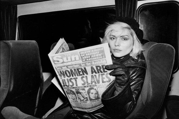 Debs holding a 'newspaper' that says women are just slaves