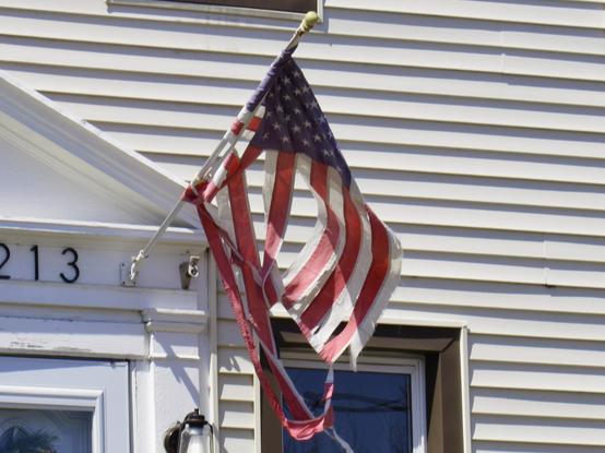 A tattered United States flag hanging over the doorway of a white house