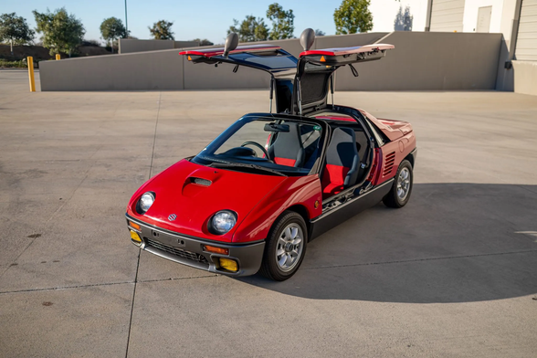 his 1993 Suzuki Cara is one of a reported 533 built. It was purchased by the seller in January 2025 and was imported to the US in March of that year. Finished in Classic Red and Venetian Gray over black and red cloth, the car is powered by a turbocharged 657cc inline-three linked with a five-speed manual transaxle. Equipment includes front and rear strut tower braces, disc brakes, 13″ Panasport alloy wheels, plastic composite body panels, gullwing doors, a glass canopy, air conditioning, crank windows, and a cassette stereo.

The Cara features plastic composite body panels, and this car is finished in Classic Red (SU) with Venetian Gray lower cladding. Exterior details include yellow fog lights, a hood scoop, gullwing doors, a full glass canopy, and straked side air intakes.