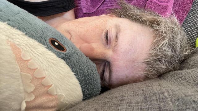 Me lying down on the sofa, cuddling my blåhaj.