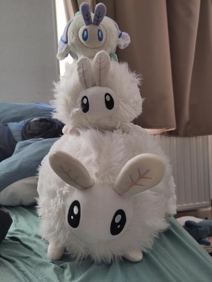 three plush moths stacked on top of each other, each moth smaller than the one below