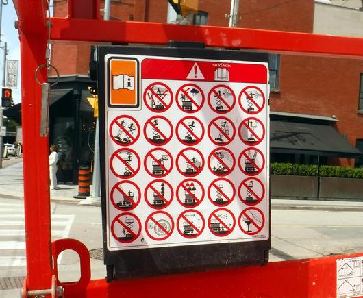 a sign attached to a Skyjack has 24 little illustrations, each with a red circle with a diagonal line through it, showing all the dumb moves you should definitely not try... i like the one in the bottom left corner -- do not dive off the platform