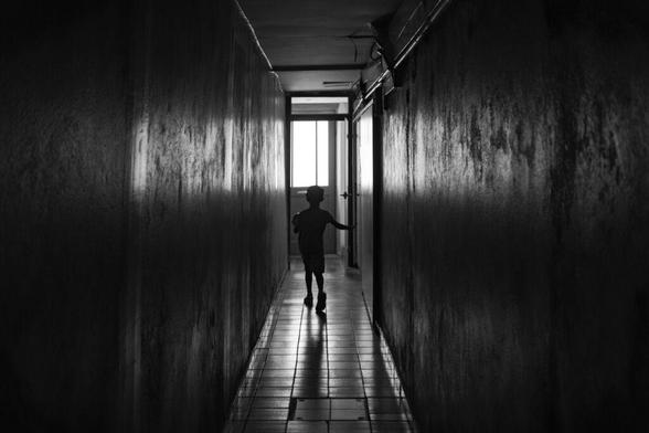 A black and white shot of our young one from behind, walking out the long, dramatically lit hallway leading to our apartment in La Rochelle.