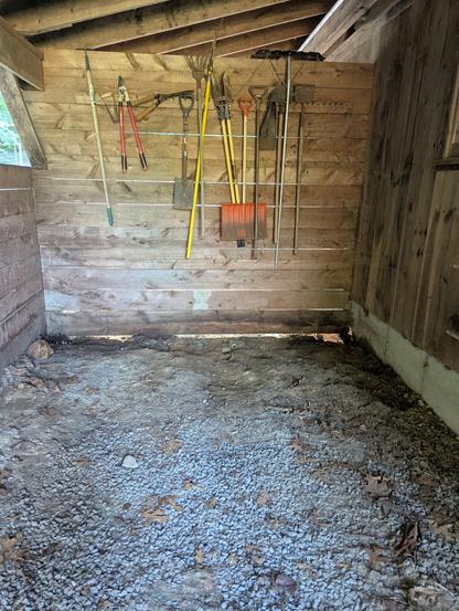Back Wall on barn under over hang repair. Large rough barn board wall with hand tools hung on it.