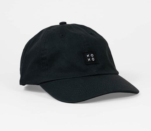Photo of a black baseball cap with a square black felt logo sewn with the letters “XOXO” in the center