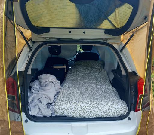 Bild från inne i bilen, bäddad säng till höger, packning till vänster.