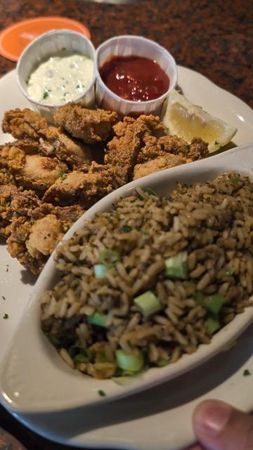 A medium fried oysters with a side of dirty rice with a lemon wedge, cocktail sauce. AND tartar sauce.