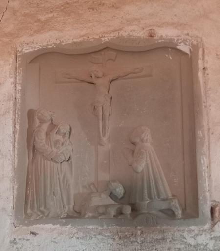 En relief från väggen i frustugan föreställande Jesus på korset och förmodligen Mariorna som sörjer honom