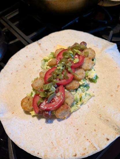 Chopped pickled jalapeno, sliced tomatoes, atop sausage, tater tots, eggs and a tortilla