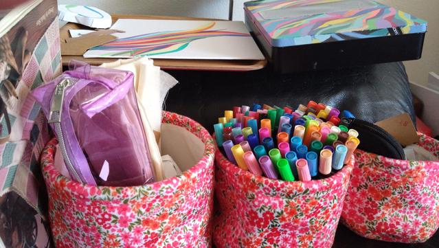 Three fabric baskets with left to right needle punch and crochet stuff, paint markers and office supplies