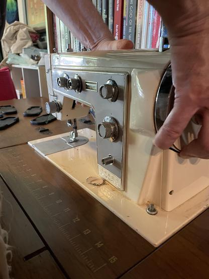 A sewing machine being held in the space where it is supposed to fit in the sewing table. It is quite heavy!