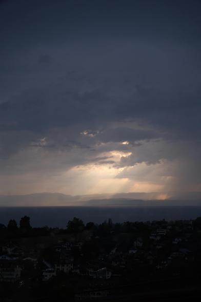 rays of sunlight shining through clouds onto a lake in the mountains at dusk