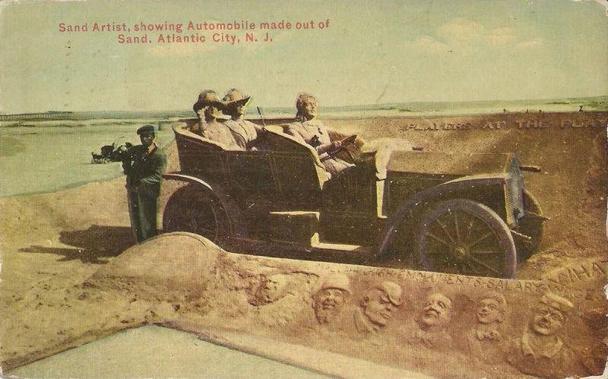 This postcard reads, "Sand Artist, showing automobile made out of Sand, Atlantic City, N.J." It shows a large sand sculpture of an early 20th-century open-top touring car. Three figures sit in the car: one in the front seat and two in the back, both wearing wide-brimmed hats. The African-American artist stands beside the sculpture wearing a hat and dark jacket. Several human faces appear at the base of the sculpture.