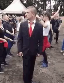 a man in a suit and tie is standing in front of a crowd of people at a concert .