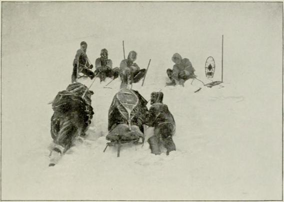 Ascending Icy Mountains.

Title: Through the first Antarctic night, 1898-1899

a narrative of the voyage of the "Belgica" among newly discovered lands and over an unknown sea about the south pole

Author: Frederick Albert Cook

A photograph showing polar expedition members in heavy fur-lined coats, gathered in deep snow with sledges and equipment, including what appears to be snowshoes on a stand.