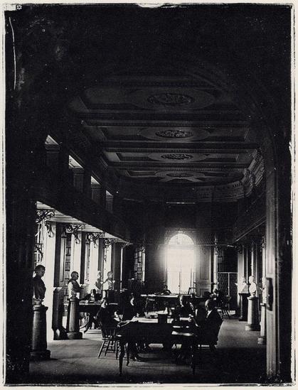 The Boston Athenaeum by Southworth & Hawes.

It is showing the interior of the Boston Athenaeum, a grand reading room with ornate coffered ceilings, arched windows letting in dramatic light, marble busts on pedestals lining the columns, and several people seated at tables reading.