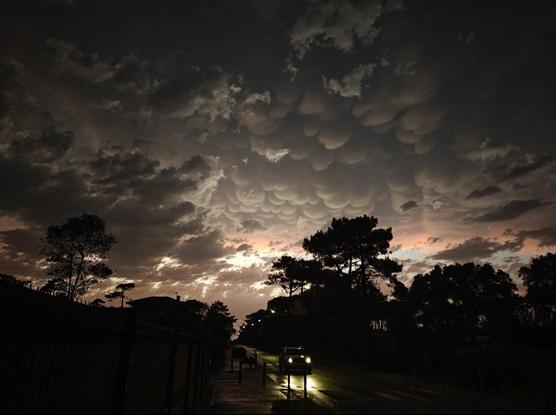 A layer of fast moving clouds below, street wet with rain