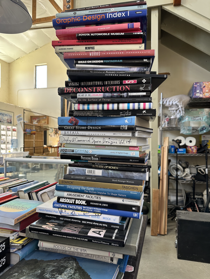 A stack of hardcover, coffee table style books over three feet tall. Titles include art, architecture, applied design, and commercial graphics.