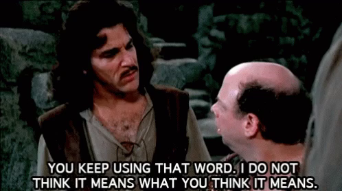 Open shirt man in waist coat mentions to bald Sicilian man that You Keep Using That Word, I Do Not Think It Means What You Think It Means