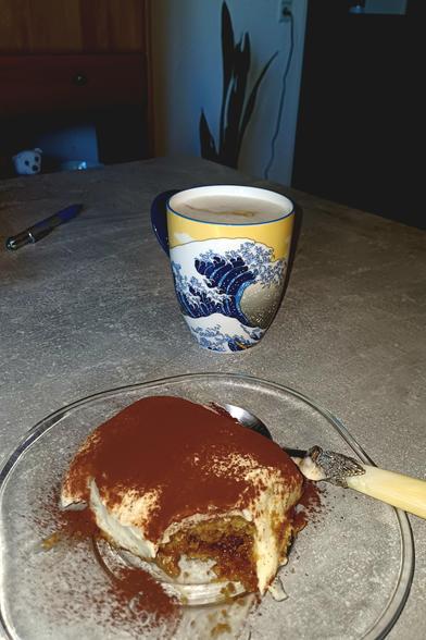 Sobre a mesa,  prato com Tiramisu e xícara com café. Tudo vegano.