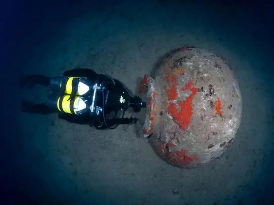 An underwater photograph featuring a diver positioned in front of a dolium, illustrating the substantial size of the vessel.