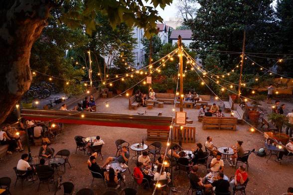 Picture of Le Taille Crayon (from their web page): people sitting at tables in a nice courtyard with trees around and lights above.