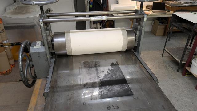 Presse à taille douce avec langes en feutres sur le rouleau et une plaque prête à imprimer sur le plateau.