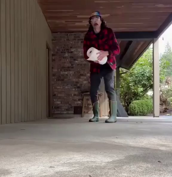 A man with glasses and a baseball cap in a red check shirt, rolls a roll of paper towel towards the camera. When the rolls stops just in front of the camera, the words 'fuck you' are visible.