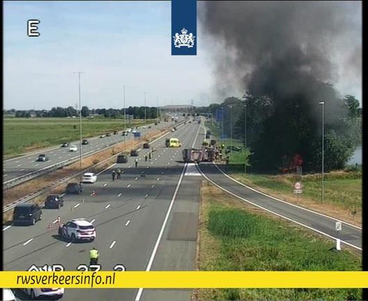 Verkeer rijdt over één rijstrook. Je ziet rookpluimen opstijgen.