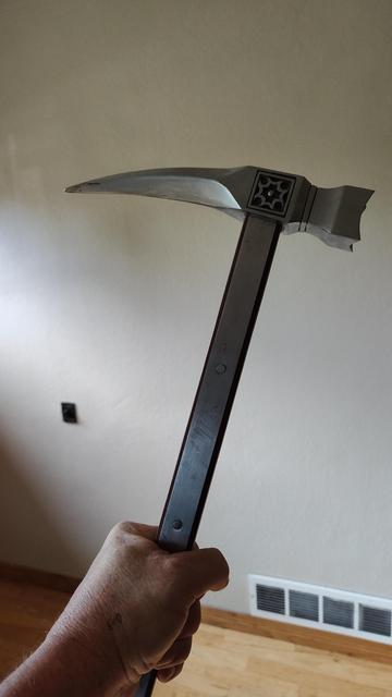 A warhammer is seen clutched by an ageing fist.